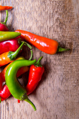 Hot chili pepper red, green, yellow scattered on an old wooden table
