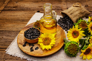 Sunflower oil in glass cruet with flower head and seeds in wooden bowl