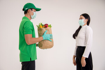 Lady recieving food  ingredients from food delivery man with wearing surgical mask and gloves both for virus preventive