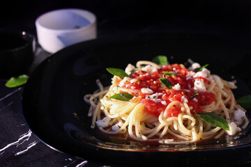 Tasty appetizing classic italian spaghetti pasta with tomato sauce, cheese and basil on plate on marble background. close up view