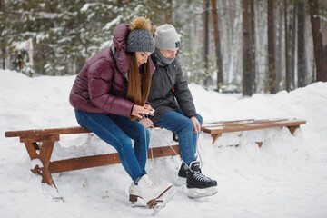 Young guy and girl with skates on a bench.