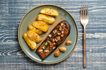 Oven baked eggplant fries with walnuts, garlic and herbs in plate, top view, copy space