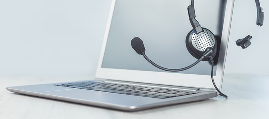 Laptop. Mockup screen and headphones on grey desk and plain background banner. Distant learning or...