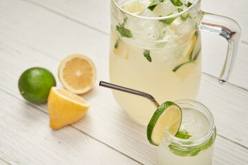 Glass and pitcher of freshly made lemonade ready to drink on a wooden table.