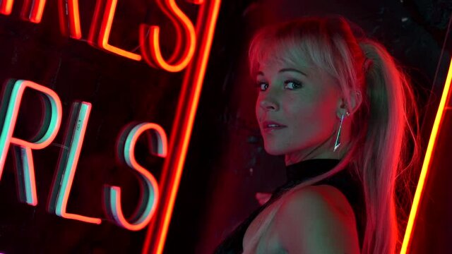blonde shy sexy lady is posing in night street with neon lights, prostitute
