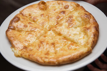 Round khachapuri with cheese lies on a platter