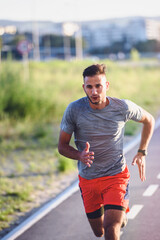 Sports man running fast outdoors on a race track