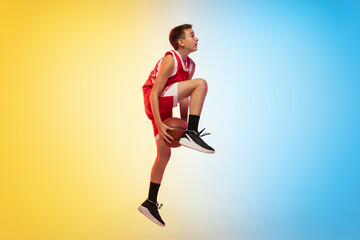 In fly. Full length portrait of young basketball player in uniform on gradient studio background....