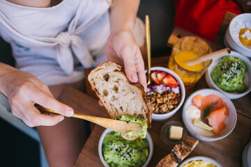 Crop woman putting avocado sauce on bread
