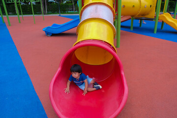 Little boy playing on playground park enjoying slider