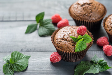 Chocolate muffins with raspberries on dark wooden background, selective focus