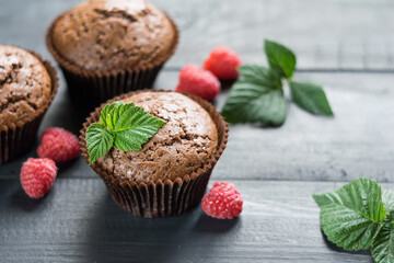 Chocolate muffins with raspberries on dark wooden background, selective focus