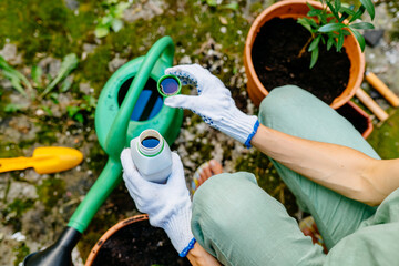Woman pours liquid mineral fertilizer, in watering can with water. Cultivation and caring for...