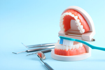 model of teeth and dental instruments and dental care products on colored background