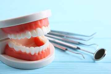 model of teeth and dental instruments and dental care products on colored background