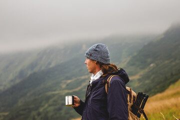 Fototapeta na wymiar Hiker holding cup with hot drink in mountain. Travel, adventure and active lifestyle concept