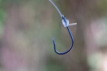 Tie A Snell Knot on fishing hook with blur background.