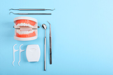 model of teeth and dental instruments and dental care products on colored background
