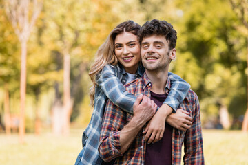woman embracing man in checkered shirt in park