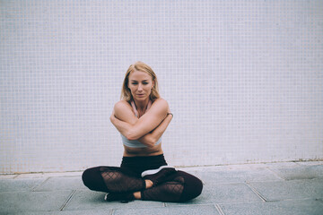 Portrait of Caucasian woman doing stretching exercises during morning energetic workout to develop flexibility and lead healthy lifestyle, motivated girl practicing sportive training at urban setting