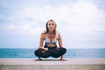 Fototapeta na wymiar Flexible woman practicing yoga on seafront