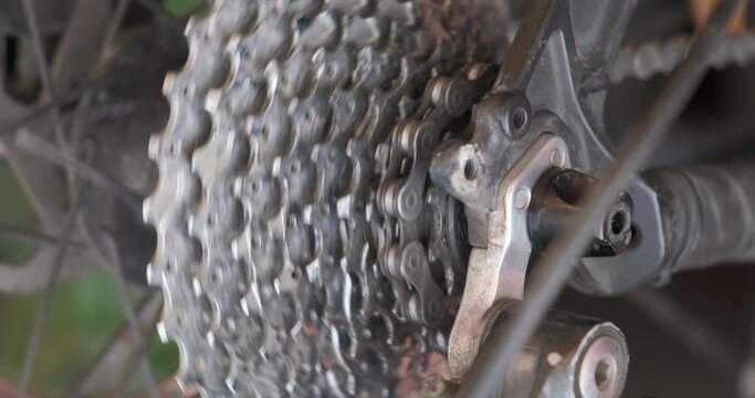 Chain moves on cogset cogs on bicycle cassette. Changing speeds, gearshift on mountain bike (MTB). Close up.