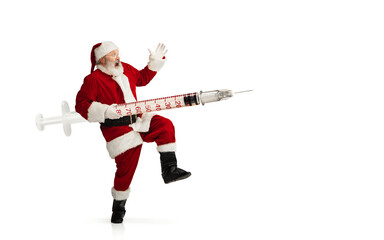 Santa Claus holding huge vaccine against COVID like Christmas gift isolated on white background. Male model in traditional costume. New Year, holidays, winter, epidemic, pandemic concept. Copyspace.