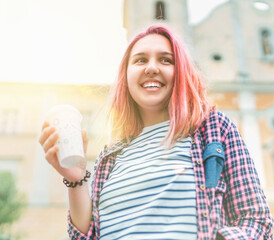 .Portrait of cheerfully smiling beautiful young female modern teenager with extraordinary hairstyle color in checkered shirt holding "coffee to go" cap. Modern teens or cheerful students concept image