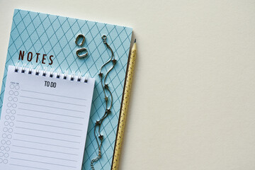 Two notepads with pencil, silver bracelet and earrings on a beige paper background. Top view. Close-up. Flat lay.
