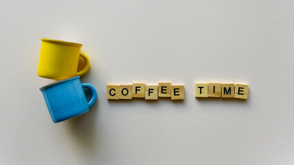 Two empty coffee cups and wooden words "Coffee time" on a beige paper background. Top view. Close-up. Flat lay.