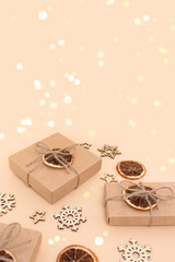 Wrapped gift boxes and wooden New Years decorations on a beige background. Festive concept with shiny golden bokeh.