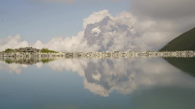 A Picturesque Landscape Of Wetterhorn Mountain In The Clouds Seen From The Fallbodensee Lake In Summer In Switzerland. - timelapse