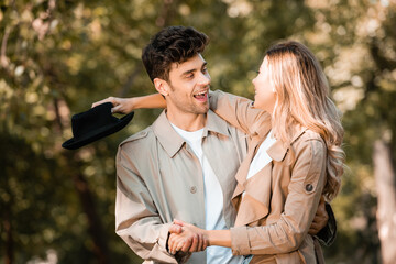 Fototapeta premium excited couple holding hands and and looking at each other in autumnal park