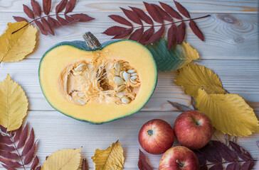 Cut ripe, yellow pumpkin on a wooden background with autumn leaves