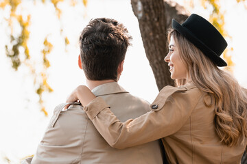 Fototapeta premium blonde woman in hat touching and looking at boyfriend outside