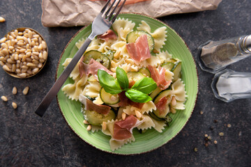 Tasty farfalle pasta with courgette, prosciutto ham, grana padano cheese and pine nuts