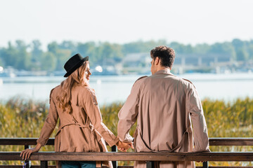 couple in trench coats looking at each other and holding hands