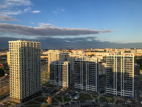 Tall Blue And White Glass Houses Are Lined Up In Height. Houses Are Made In The Same Style. New Microdistrict, Houses With Panoramic Windows. Against The Background Of Dark Clouds