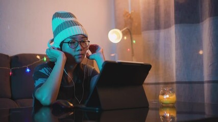 Young female dj and music producer working from home on a laptop due to coronavirus pandemic outbreak. Hip hop style girl listening to music on headphones and a computer.