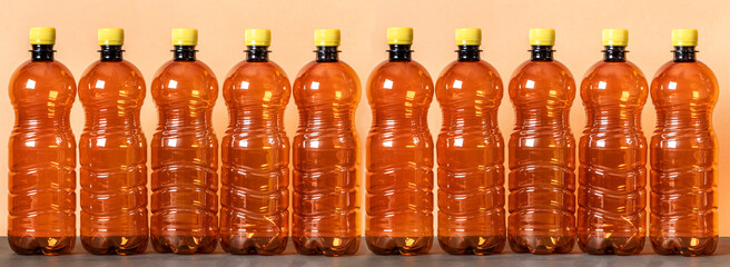 Empty brown plastic bottles stand in a row on a beige background. Banner.