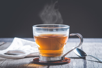 imagen de Té caliente con mascarilla de proteccion sobre la mesa de madera