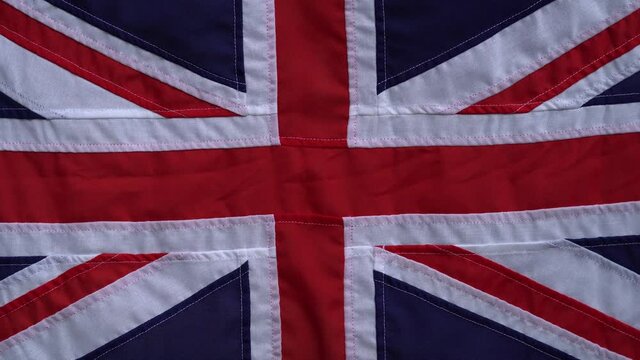 Rustic sewn UK Union Jack flag shot handheld straight on in a gentle breeze.