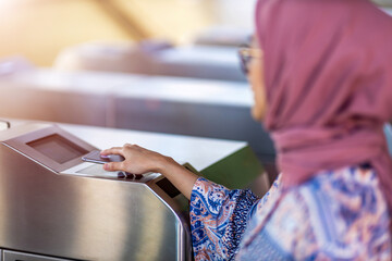 Muslim woman checking out at metro station using mobile phone
