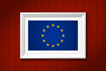 The image of the flag of the European Union in a white picture frame on a red wall background