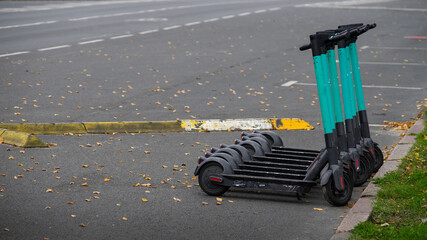 Photograph of eight generic, cyan . blue color electric scooters parked on the street.