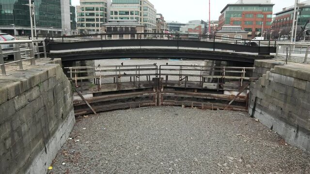 Picturesque scene of dried waterway lock by thick stone walls and gravel ground by downtown city center Dublin, handheld pan down