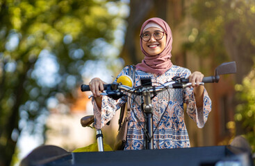 Confident Muslim woman using cargo bike in urban area
