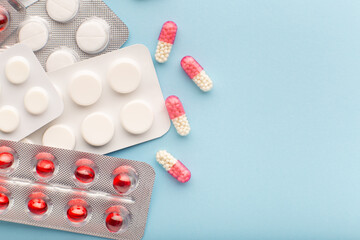 Top view colored pills and capsules on blue background, copy space. Background of blisters of pharmaceutical pills