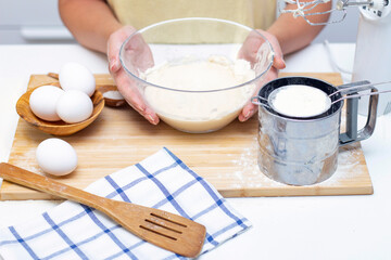 Fototapeta na wymiar Home cooking concept. Female hands prepare homemade dough on a floured wooden board. Close-up.