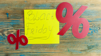 The words Black Friday handwriting text close up on yellow sticky note with red sign percent.